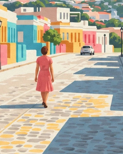 A woman in a pink dress on the cobbled street between colourful houses and a white car