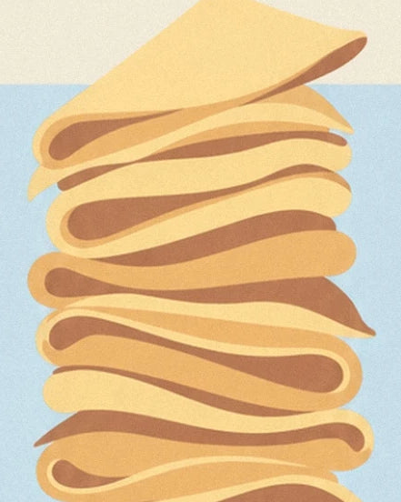 The top of a stack of golden crêpes with soft folds against a pale blue background
