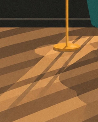 The golden base of a floor lamp and its long shadows on the honey-coloured parquet